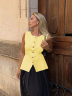 Women's sleeveless button-front peplum vest with gold buttons, tailored fit