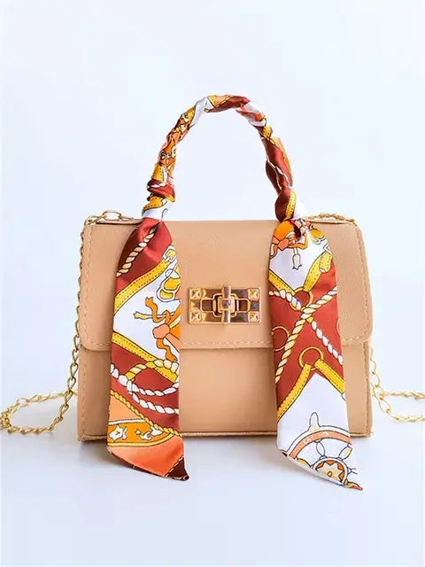 Women's brown leather handbag with gold clasp and scarf-wrapped handle