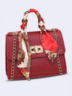 Women's brown leather handbag with gold clasp and scarf-wrapped handle