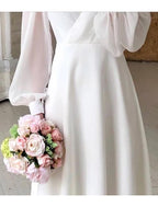 Women's white long sleeve flowing wedding dress with V-neckline, maxi bridal gown