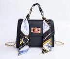 Women's brown leather handbag with gold clasp and scarf-wrapped handle