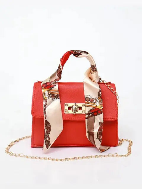 Women's brown leather handbag with gold clasp and scarf-wrapped handle