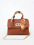 Women's brown leather handbag with gold clasp and scarf-wrapped handle