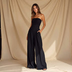 Women's strapless jumpsuit with fitted bodice and flowy wide legs, available in navy, black and beige